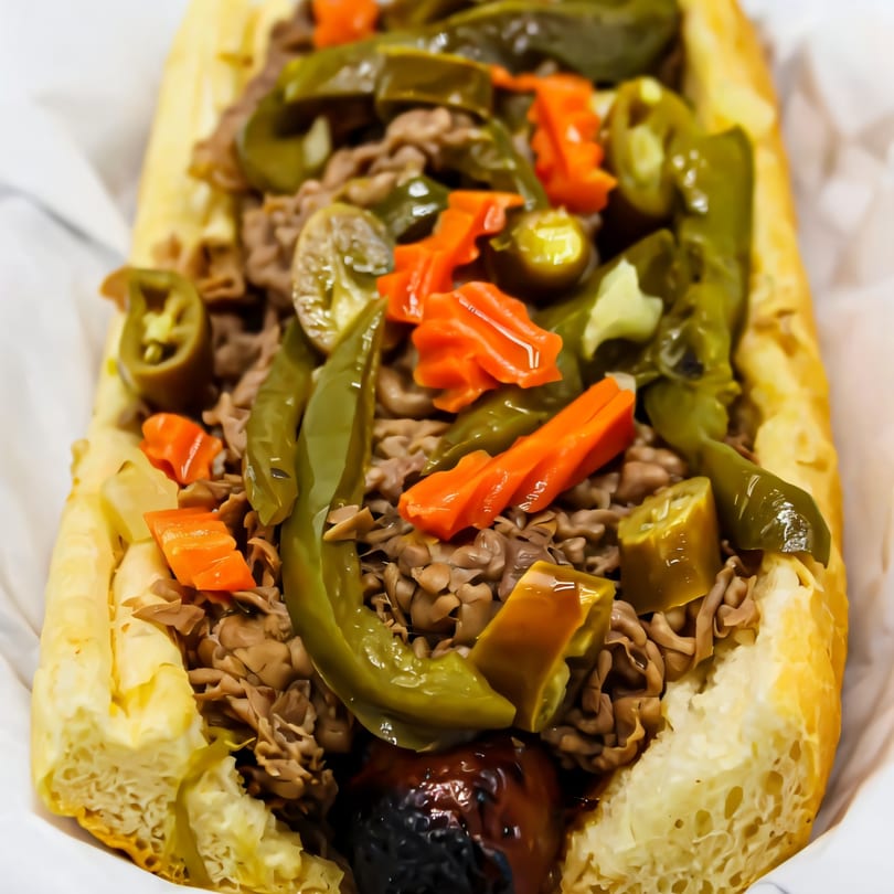 Close-up of a CHICAGOland Hotdogs & More Italian beef sandwich with giardiniera and sweet peppers.